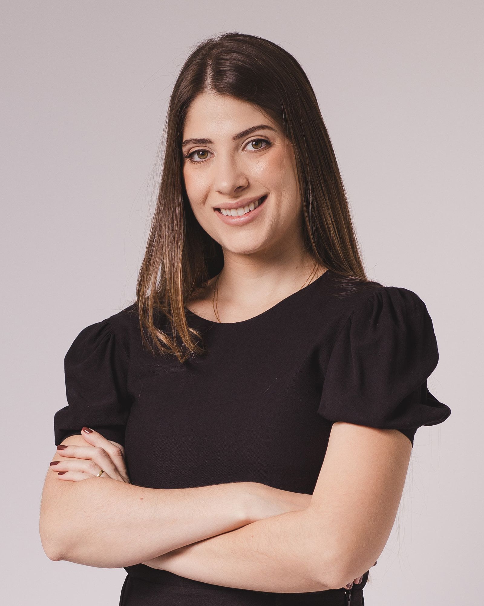 Caroline Firmino, consultora de sono infantil, de braços cruzados, sorrindo para a câmera.
